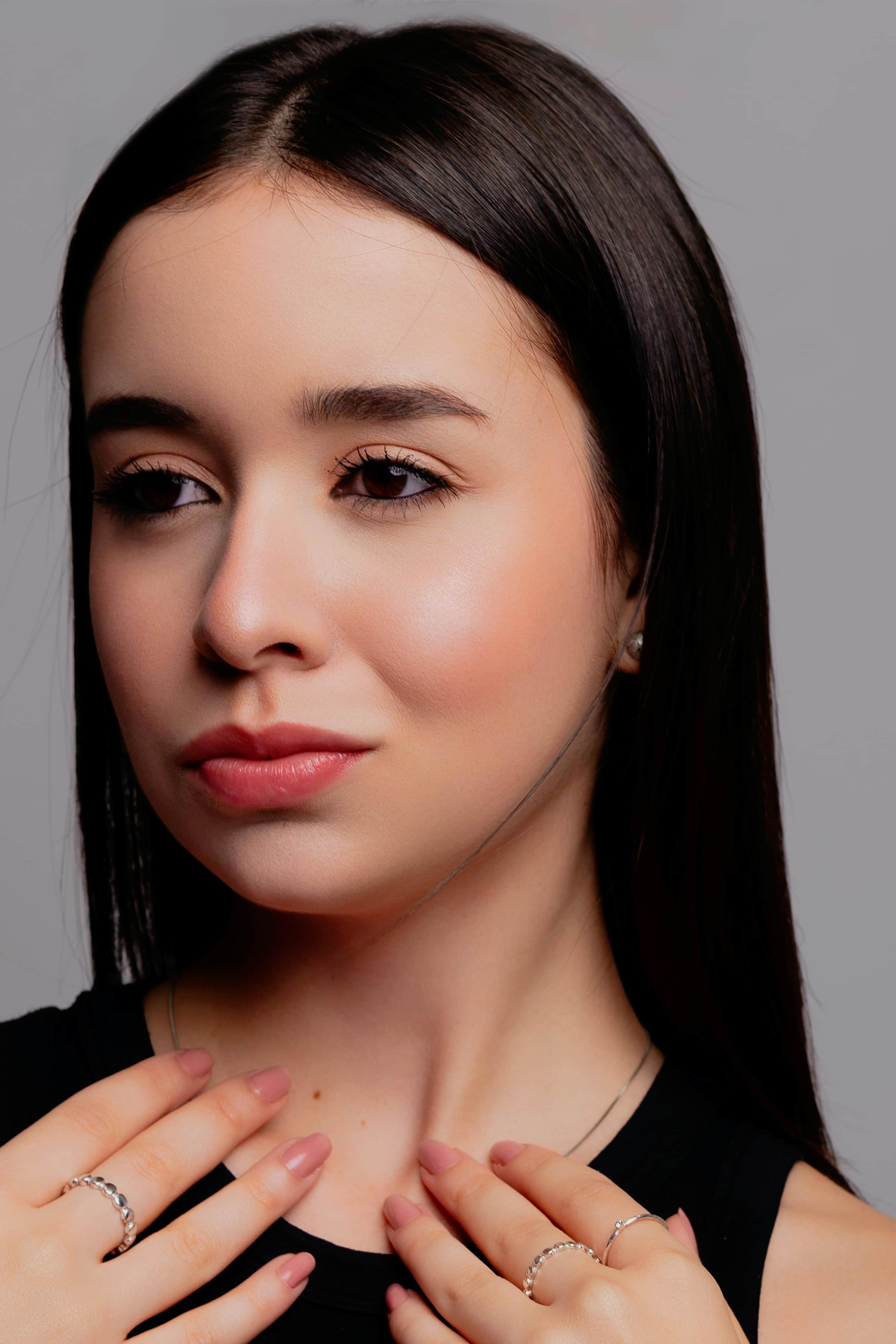 Foto de uma jovem mulher com pele clara e cabelos longos, olhar suave e cabelo liso escuro, transmitindo elegância e beleza natural.