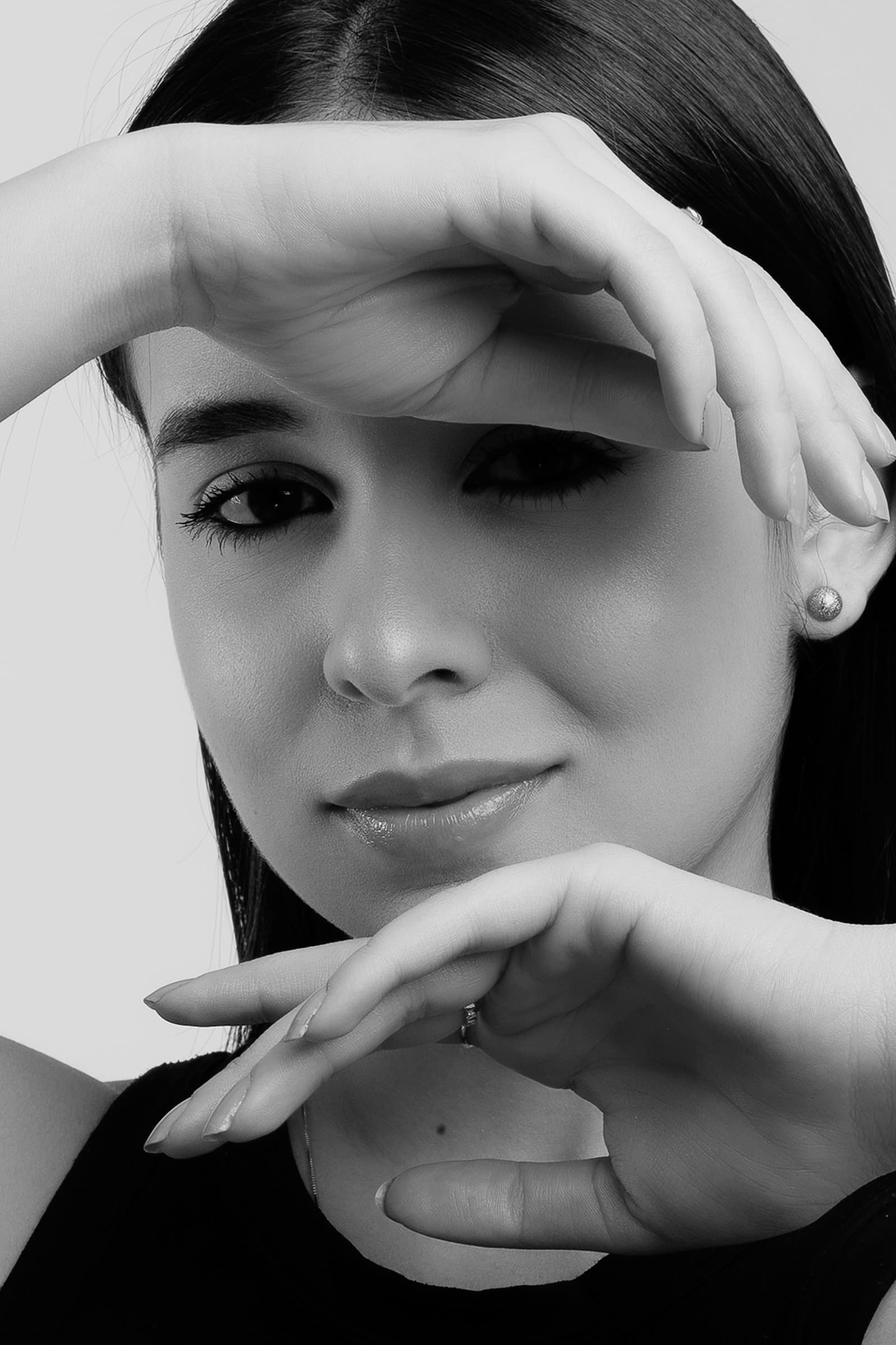 Foto de uma jovem mulher com pele clara e cabelos longos, fazendo uma pose artística na foto em preto e branco.